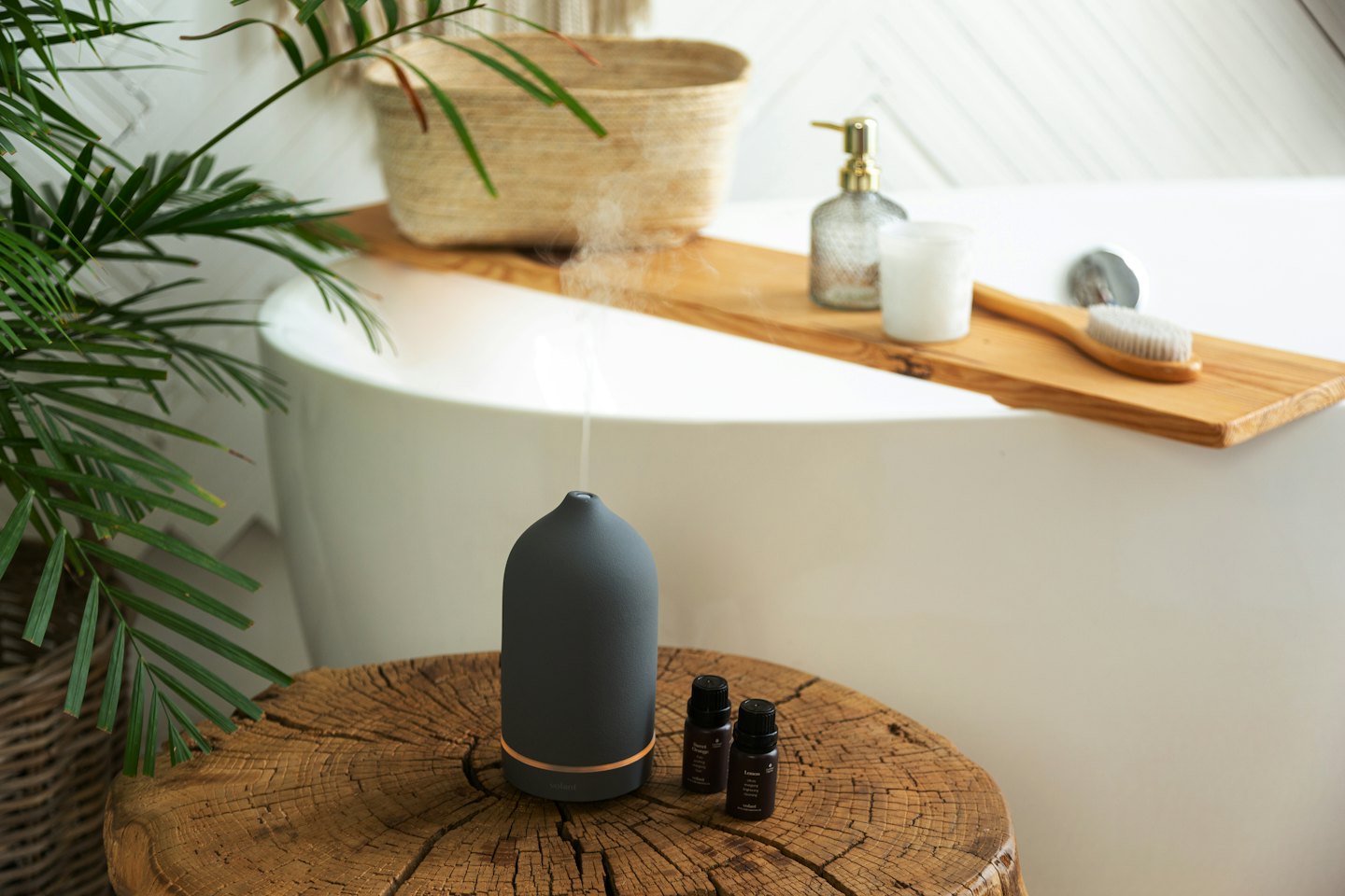 Essential oil diffuser and amber bottles on a wooden stump.